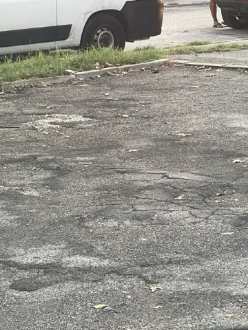 Asfalto dissestato e profondo avvallamento in centro parcheggio